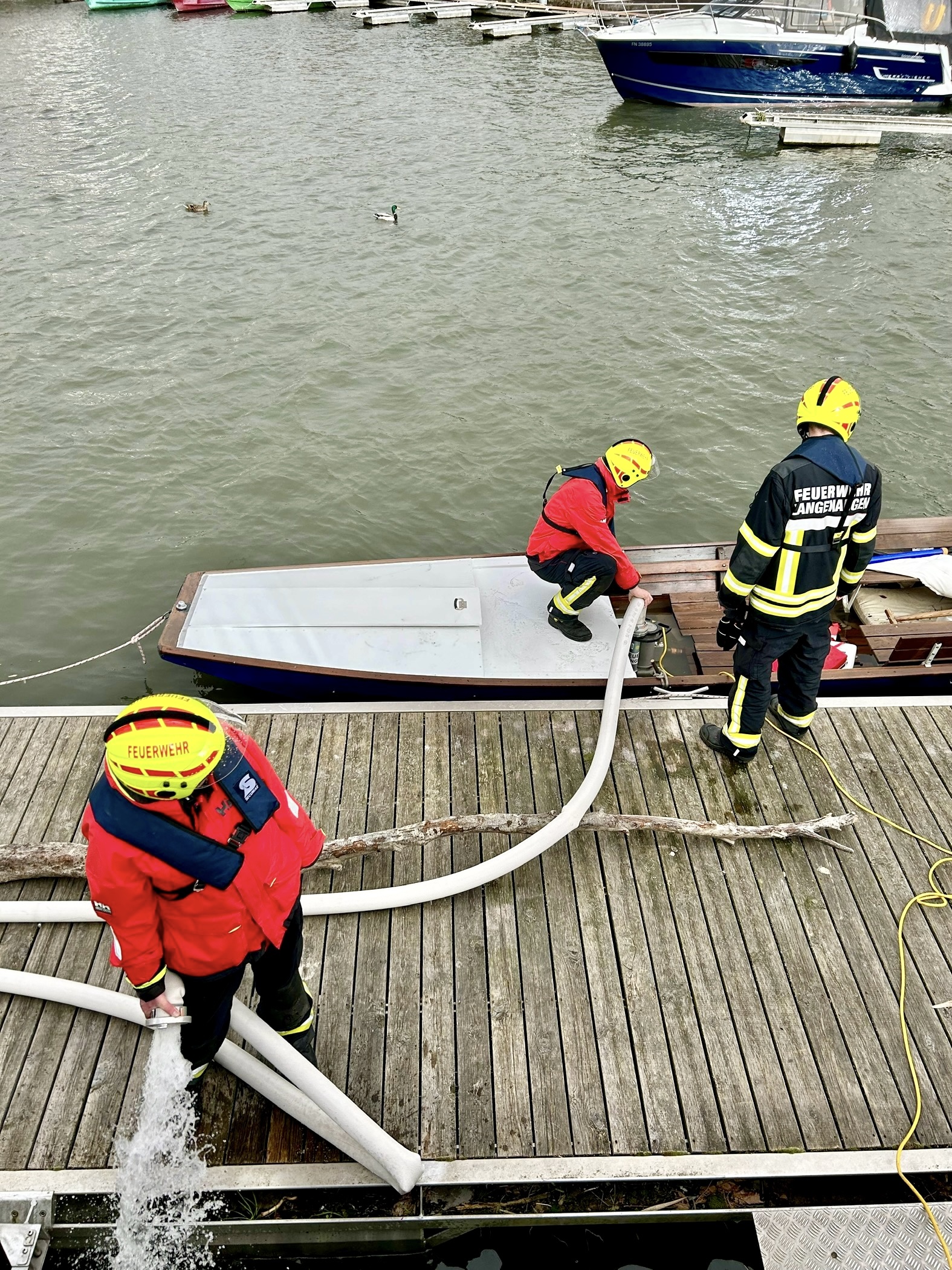 Zu sehen ist der Havarist und die Feuerwehrangehörigen wie sie sein Boot auspumpen.