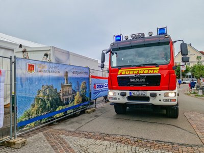 Das Löschfahrzeug steht mit Blaulicht auf der Straße. Das Festgelände des Festufer Arguna grenzt unmittelbar an. 