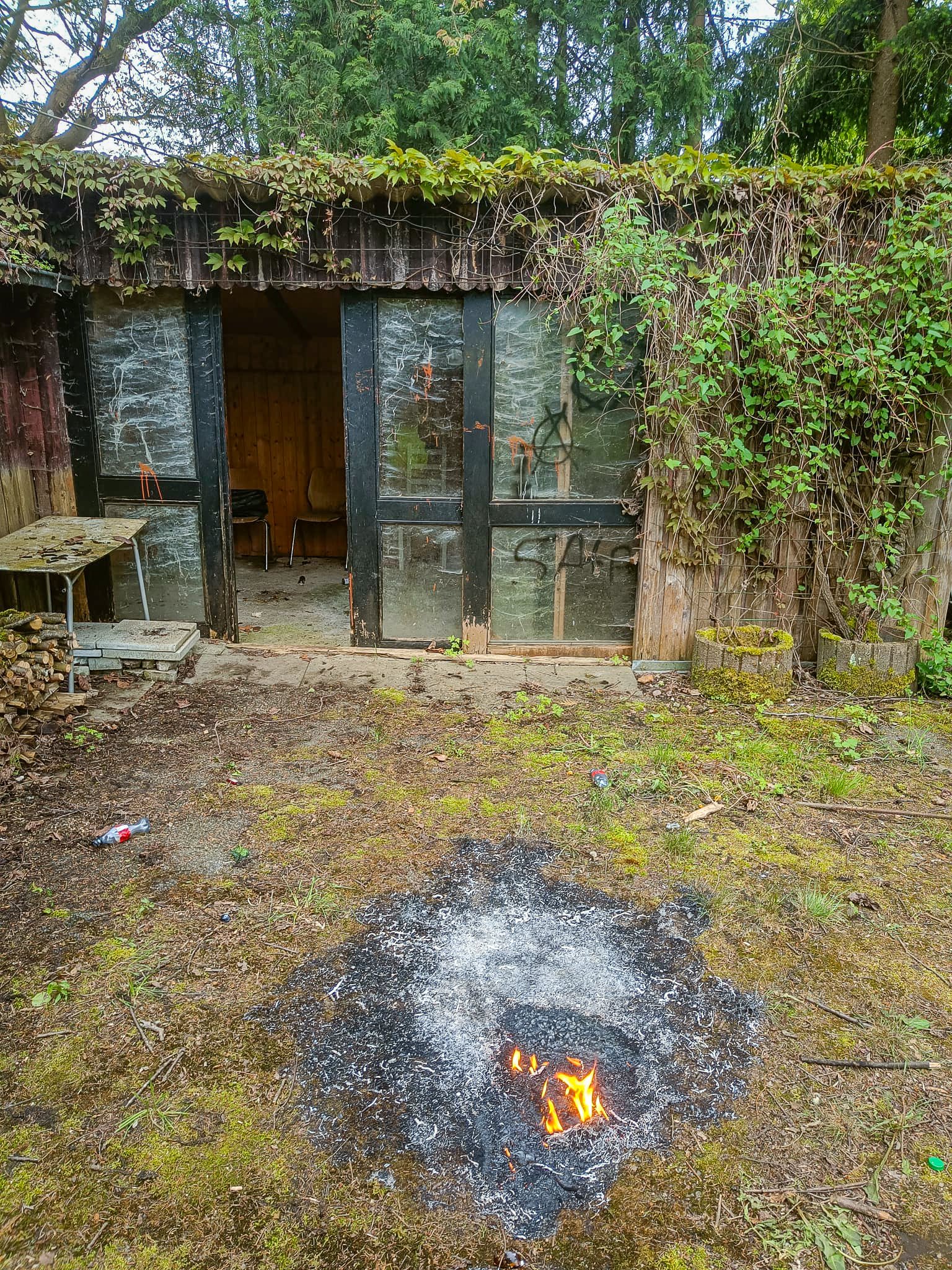 Reste von brennendem Unrat in der Nähe einer Gartenlaube