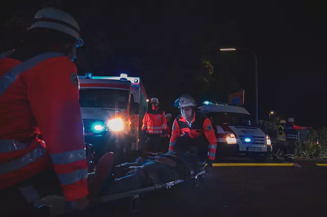 Einsatzkräfte des DRK heben einen Verletztendarsteller auf einer Trage hoch. Im Hintergrund ist ein Rettungswagen zu sehen.