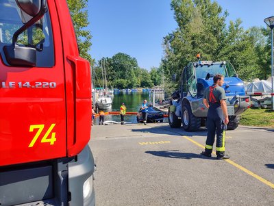 Gerätewagen-Transport im Vordergrund. Im Hintergrund ist ein PKW im Wasser und mehrere Einsatzkräfte zu sehen.