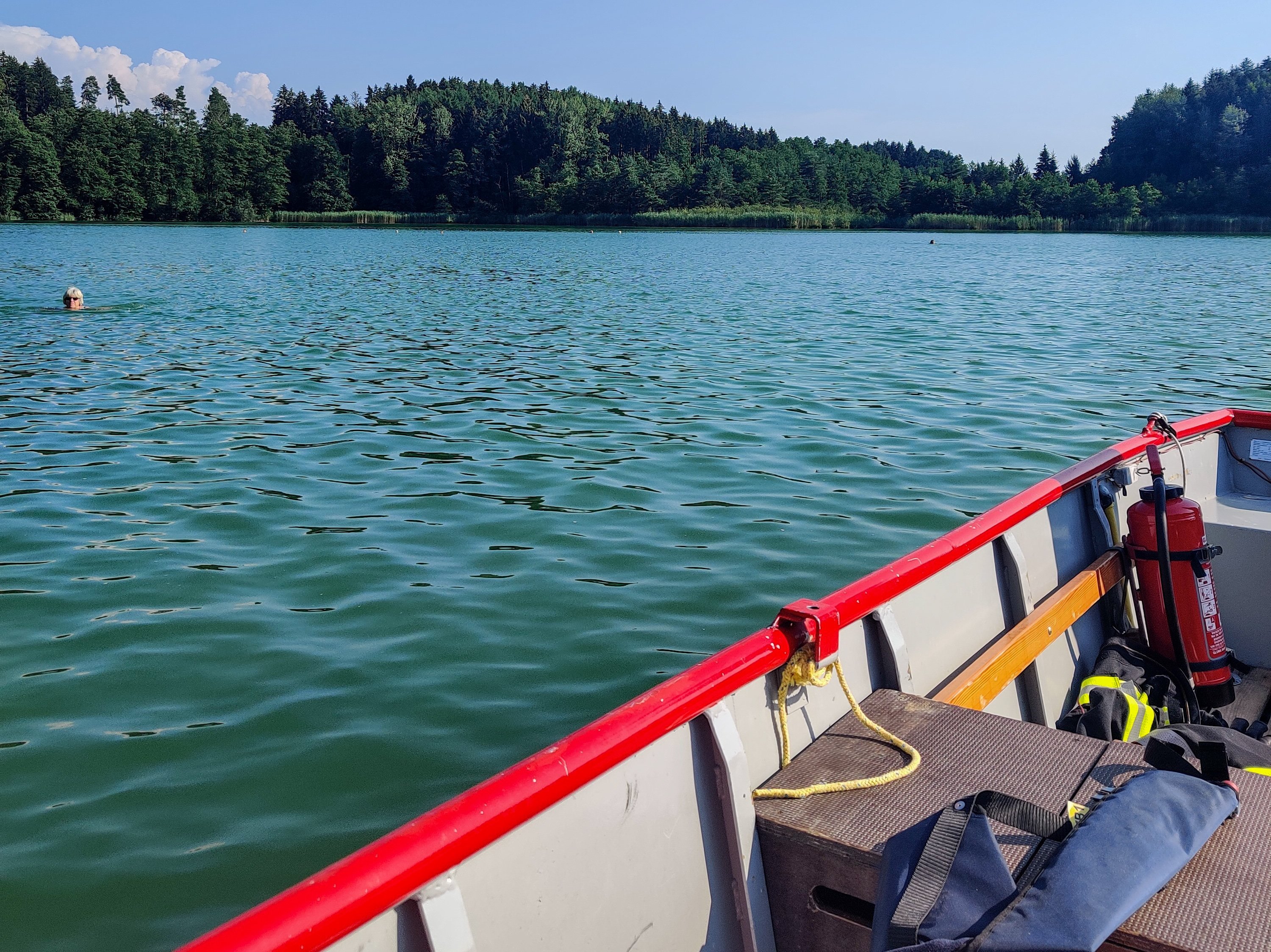 Der Degersee. Im Hintergrund das Ufer und Wald. Das Rettungsboot der Feuerwehr im Vordergrund.