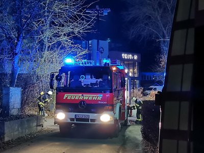 Löschfahrzeug steht mit Blaulicht auf einer Straße.