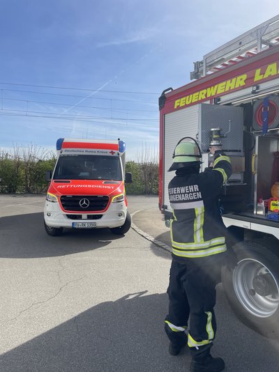 Zu sehen ist ein Mitglieder der Feuerwehr Langenargen wie er sich am LF 1/42 die Hände wäscht. Im Hintergrund ist ein Rettungswagen zu sehen.