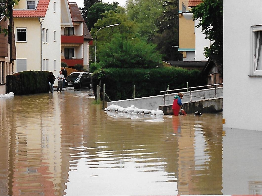 Straßen sind überflutet, Sandsackbarrieren schützen die Gebäude.