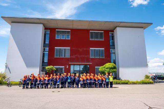 Gruppenbild aller Jugendlichen der Jugendfeuerwehren aus Eriskirch, Kressbronn und Langenargen vor dem Gebäude der Firma Strabag. Im Hintergrund 