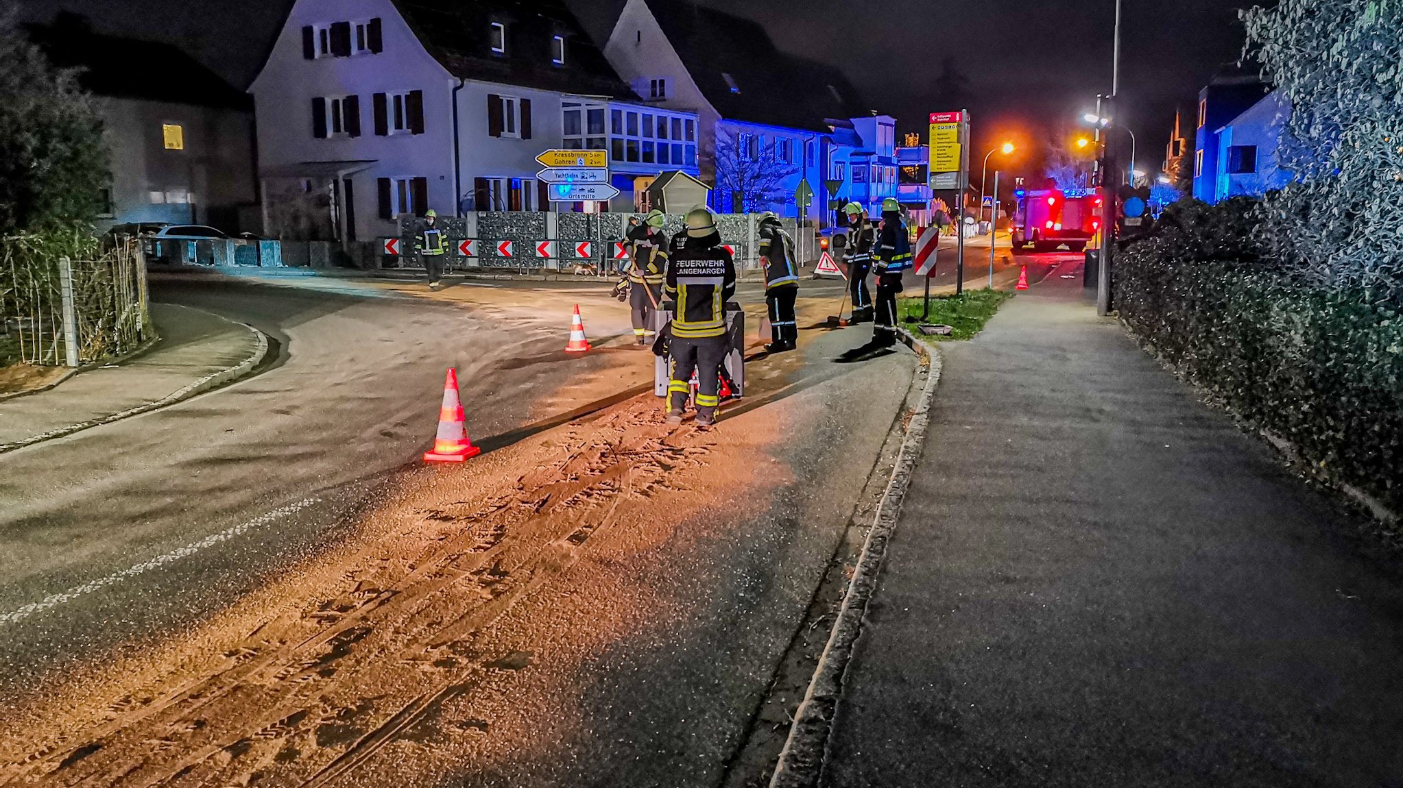 Feuerwehrleute beseitigen eine Ölspur auf der Straße.