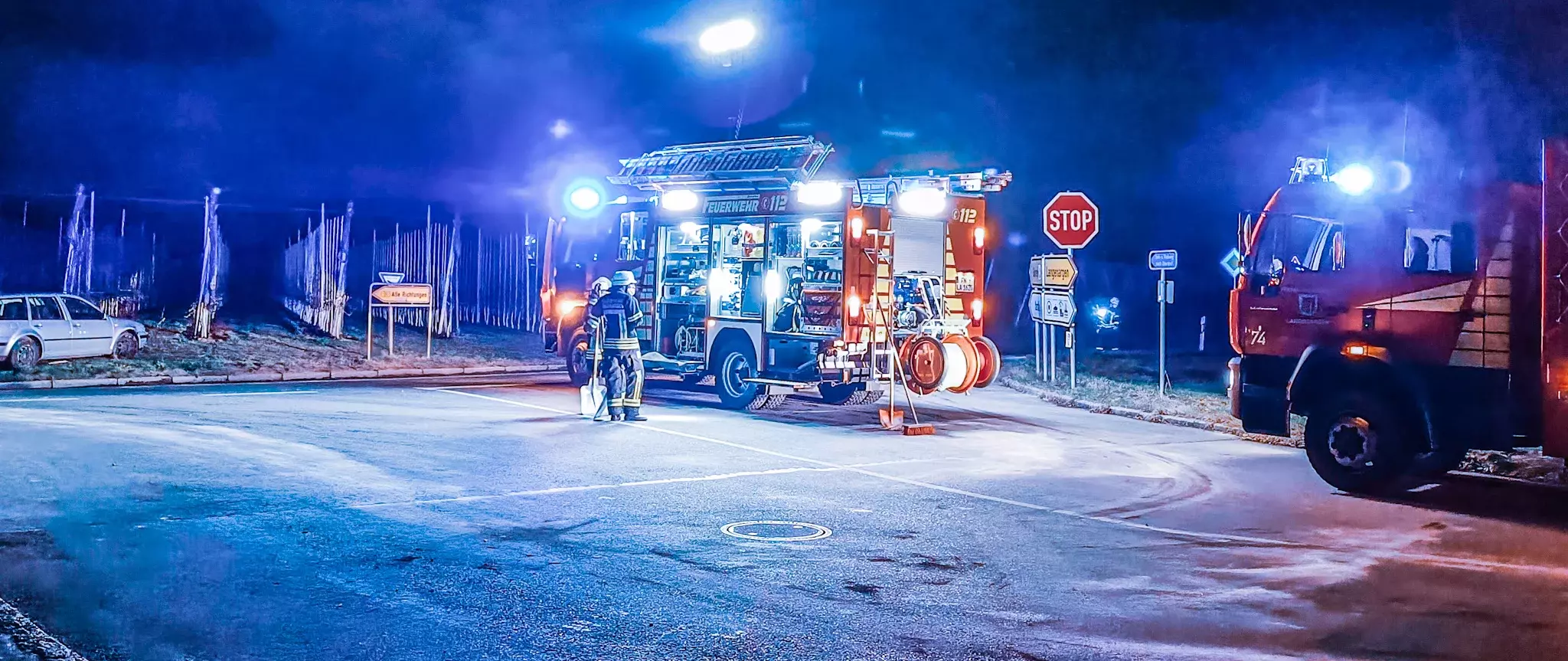 Ein Löschfahrzeug steht bei Nacht mit Blaulicht auf einer Straße.