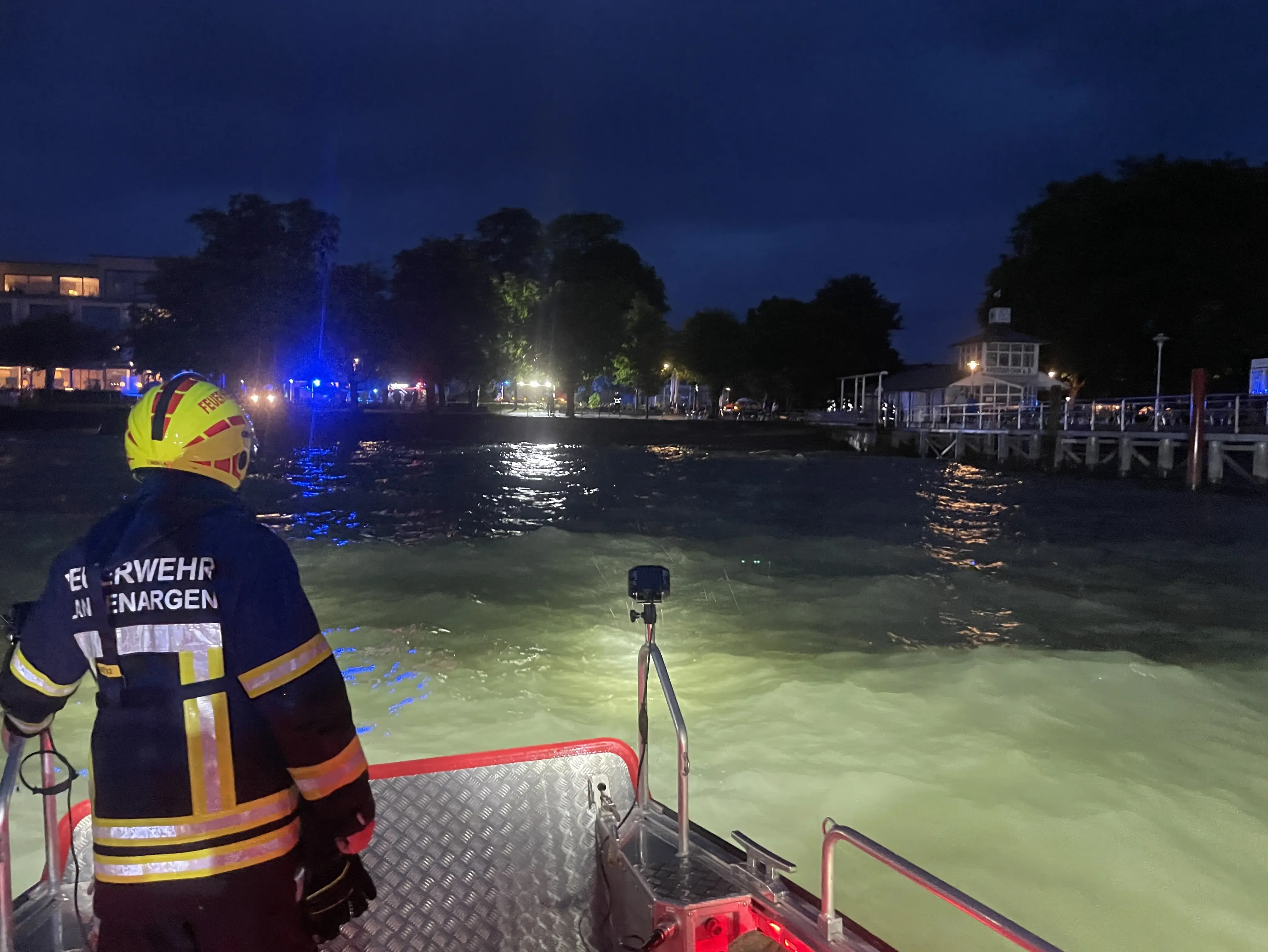 Zu sehen ist ein Feuerwehrangehöriger auf dem MZB vor Kressbronn. Im Hintergrund das Blaulicht der weiteren Kräfte.