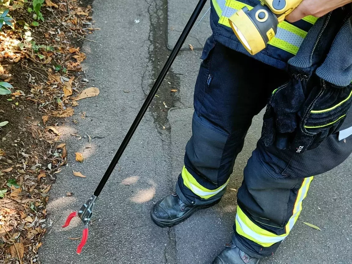 Ein Feuerwehrmann hält eine Handlampe und eine Zange in der Hand.