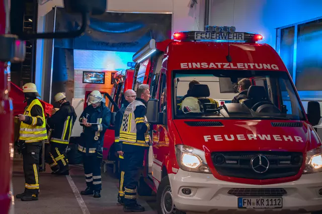 Am Einsatzleitwagen sind mehrere Einsatzkräfte beschäftigt. Auch der Einsatzleiter steht dort. 