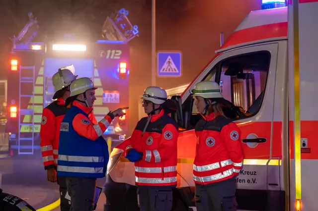 Der Gruppenführer der DRK-Einheit erteilt seiner Mannschaft einen Befehl. Im Hintergrund der Rettungswagen des DRK und das Löschfahrzeug 1/44.