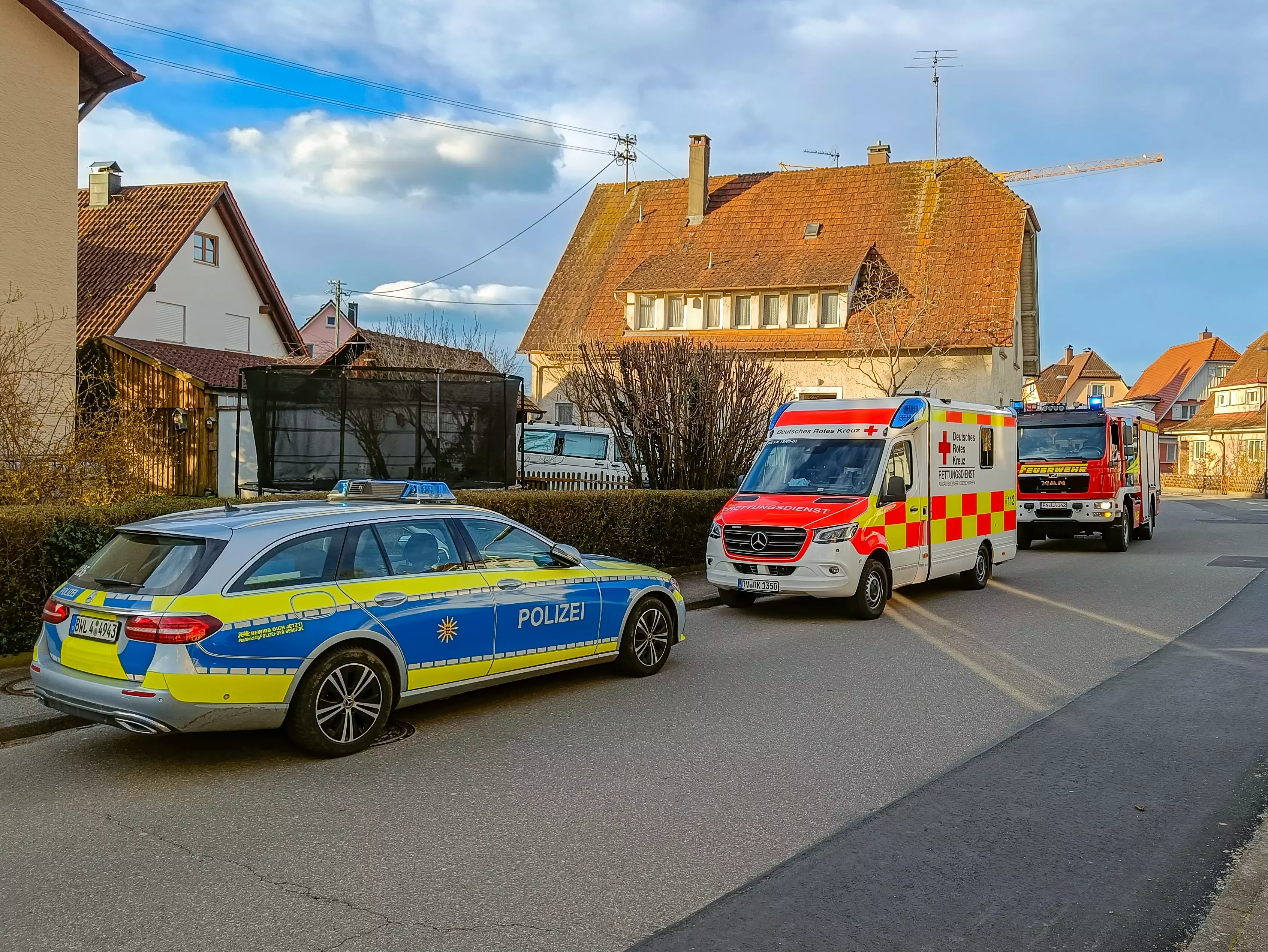 Polizei, Rettungsdienst und Feuerwehr stehen auf einer Straße.