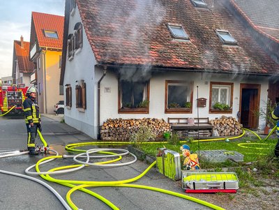 Zu sehen ist das Brandobjekt, wie dunkler Rauch aus den Fenstern im EG kommt.