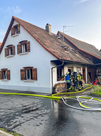 Zu sehen ist wie die Angehörigen der Feuerwehr vor dem Brandobjekt arbeiten.